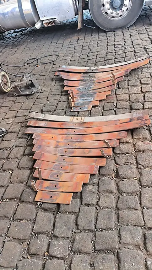 Lâminas de feixe de mola desmontadas e organizadas no pátio da Faísca